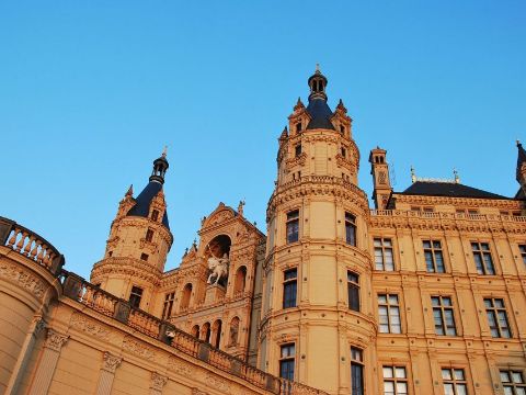 Schloss Schwerin, Blick von unten auf einen Turm vor blauem wolkenlosen Himmel.